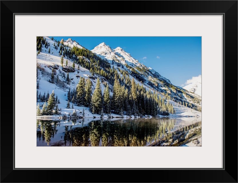 Summer snow on pine trees and the mountain side at the edge of Maroon Lake in the Maroon Bells, Aspen, Colorado.