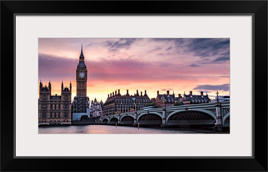 Panoramic photograph of Big Ben and the Westminster Bridge with a pink and purple sunset.