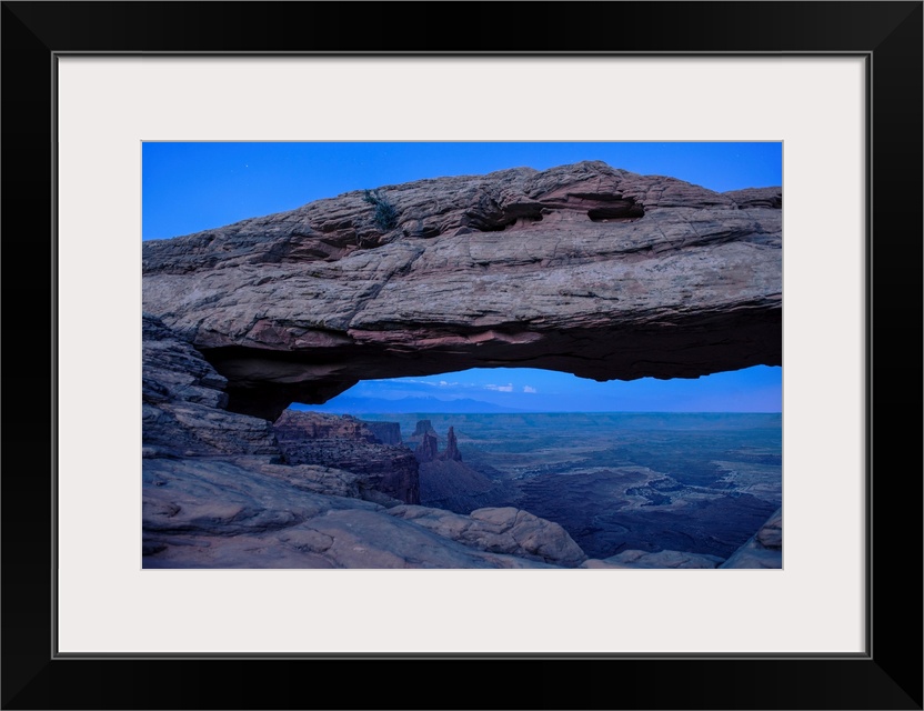 View of rock formations in Buck Canyon, framed by the Mesa Arch in Canyonlands National Park, Moab, Utah.