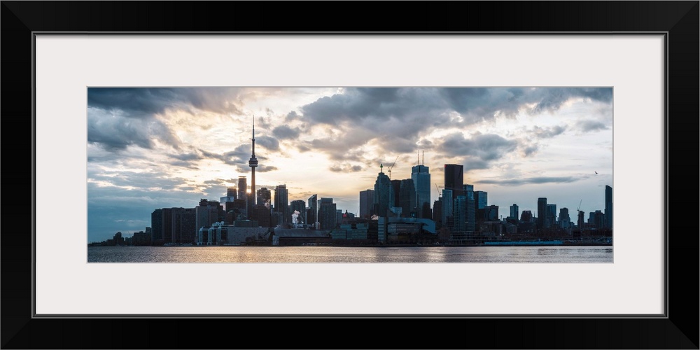 Toronto city skyline under a dramatic sunset with clouds overhead, Ontario, Canada.