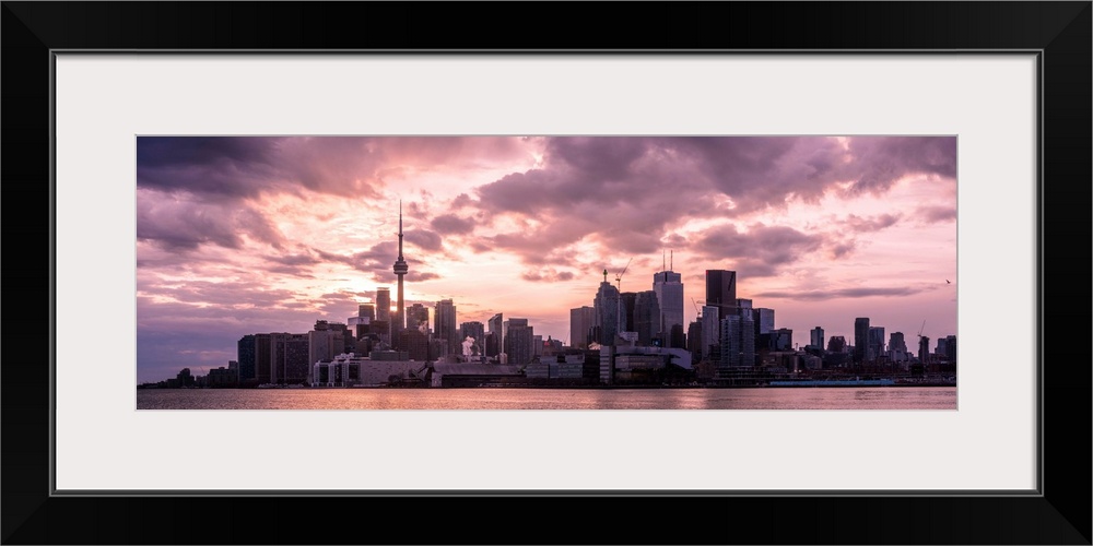 Toronto city skyline under a dramatic sunset with clouds overhead, Ontario, Canada.