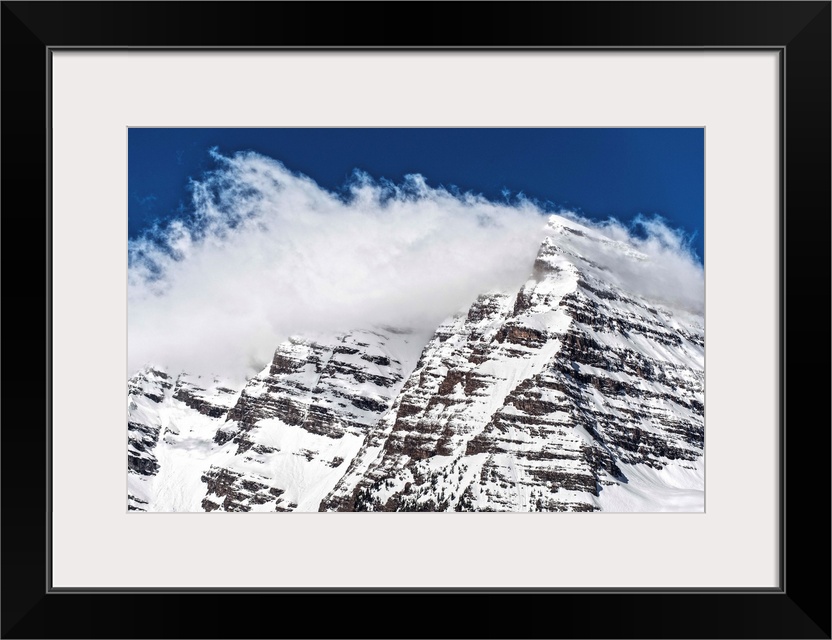 Wind-blown snow on the peaks of the Maroon Bells under a blue sky in Aspen, Colorado.