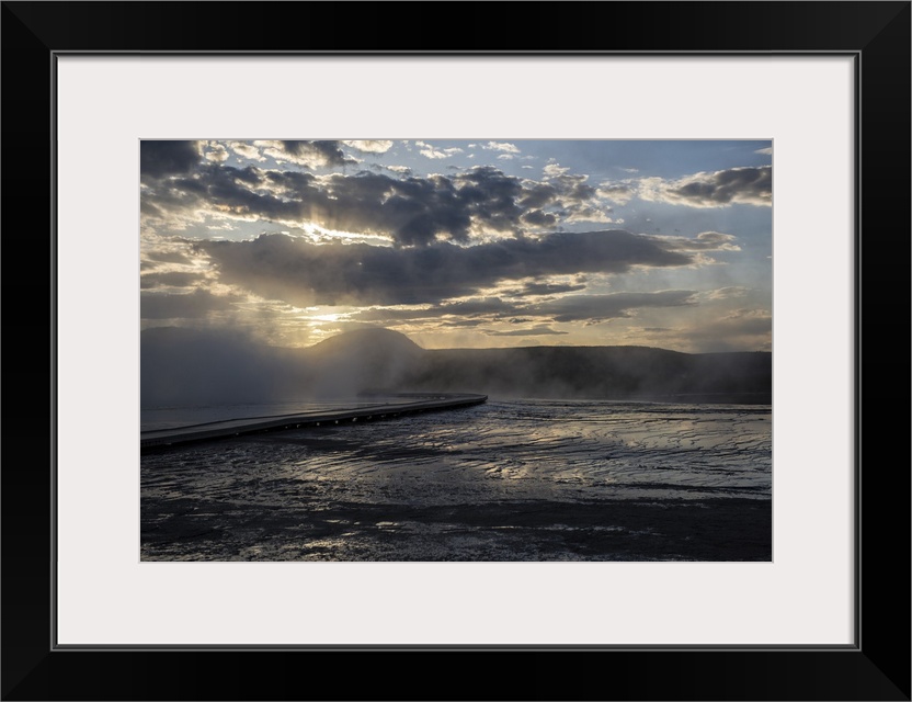 The sun rays peeking over hot springs at Yellowstone National Park.