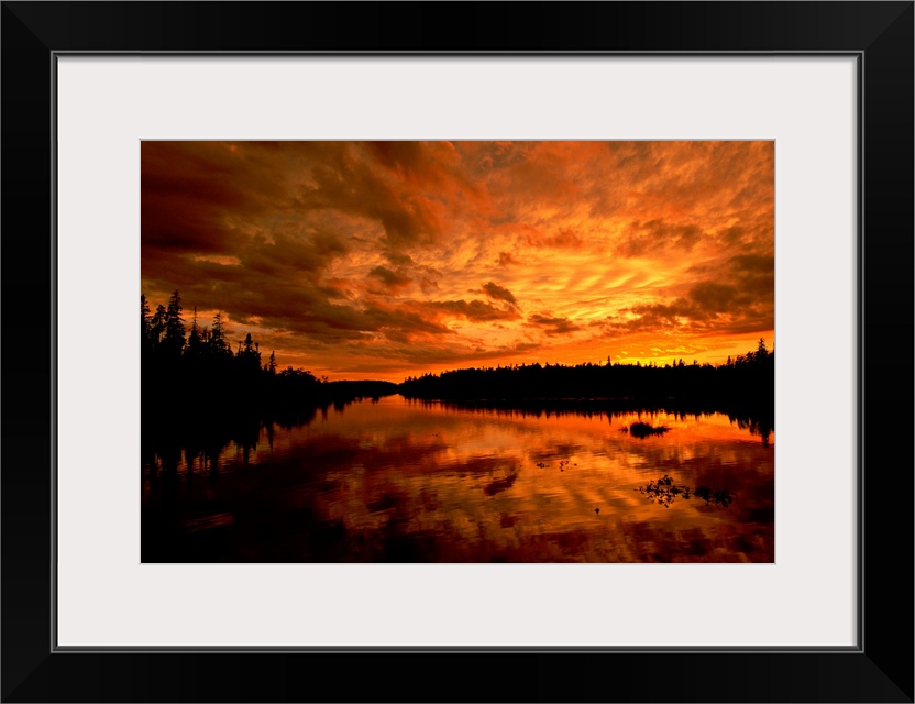 Horizontal photograph from the National Geographic Collection of a golden sunset over a lake, under a sky full of scattere...