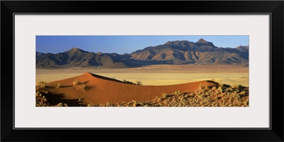 Panoramic view over orange sand dunes towards mountains, Namibia, Africa