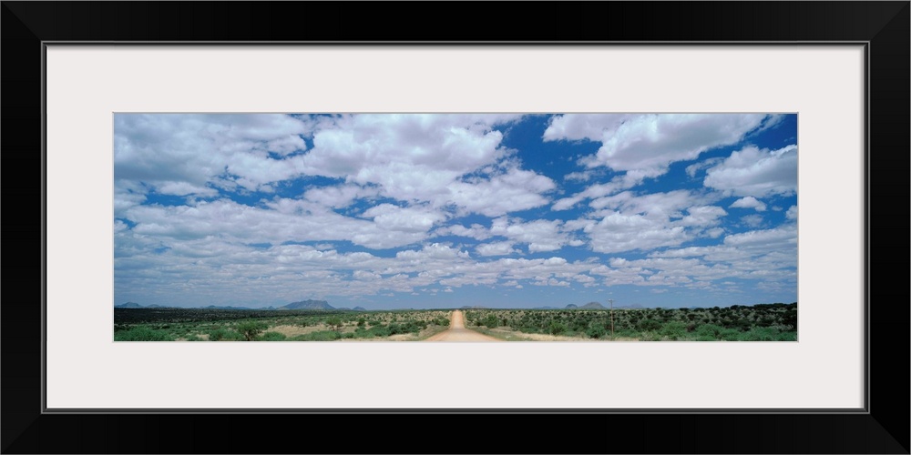 Straight gravel road cutting across grassy plain near Windhoek, Namibia