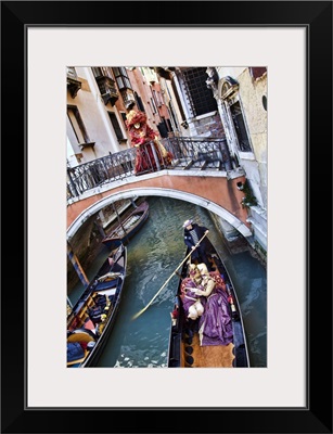 Couple in Masquerade outfits kissing in Gondola underneath bridge, Venice, Italy
