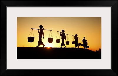 Female workers with baskets at sunset in Bagan, Burma