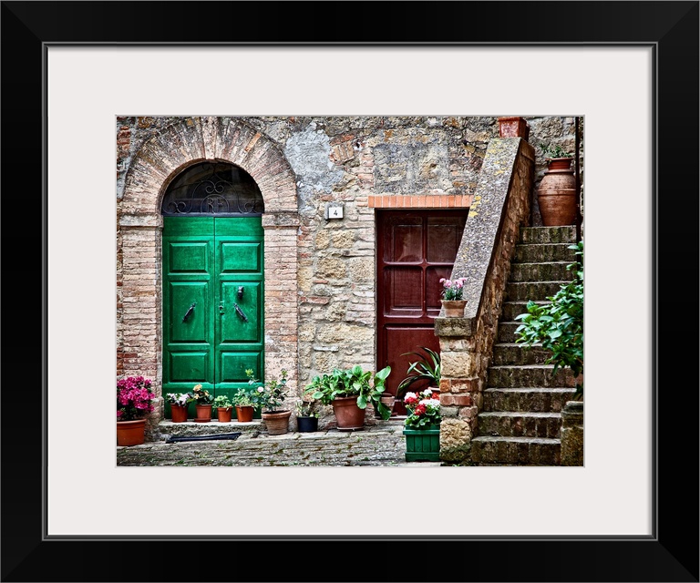 A rustic city street and ancient home built from stone and brick with brightly painted doorways lined with plants in terra...