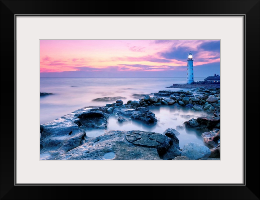 Lighthouse On Rocky Coastline At Sunset.