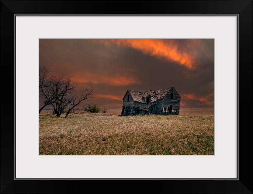 An old abandoned farm house with stormy skies at sunset in the Canadian prairies.