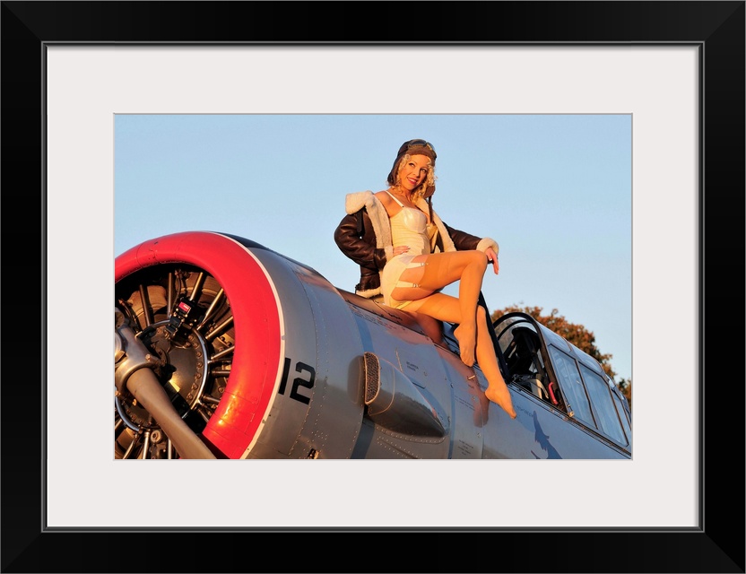 1940's style aviator pin-up girl posing with a vintage World War II T-6 Texan aircraft.