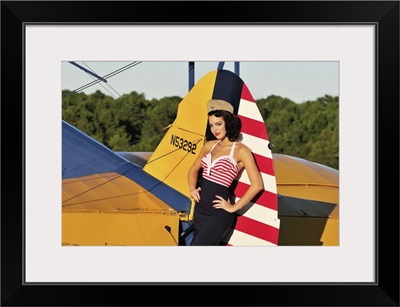 1940's style pin-up girl leaning on the tail fin of a Stearman biplane