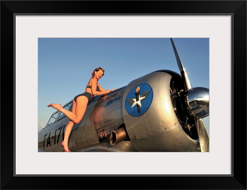 1940's style pin-up girl standing on the wing of a World War II T-6 Texan.