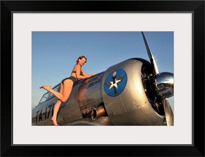 1940's style pin-up girl standing on the wing of a World War II T-6 Texan