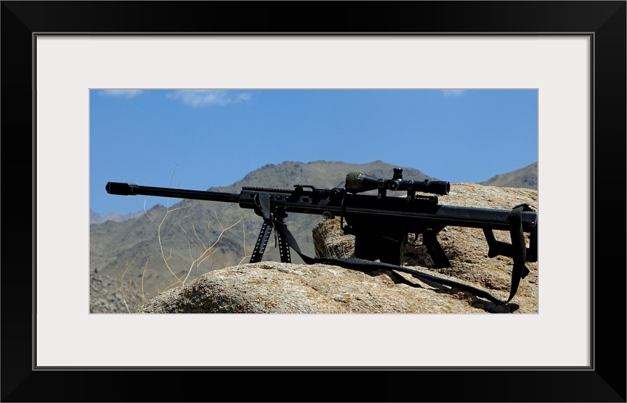 Wall docor of a sniper rifle that is propped up on a stony ridge over looking mountains in Afghanistan that was used in a ...