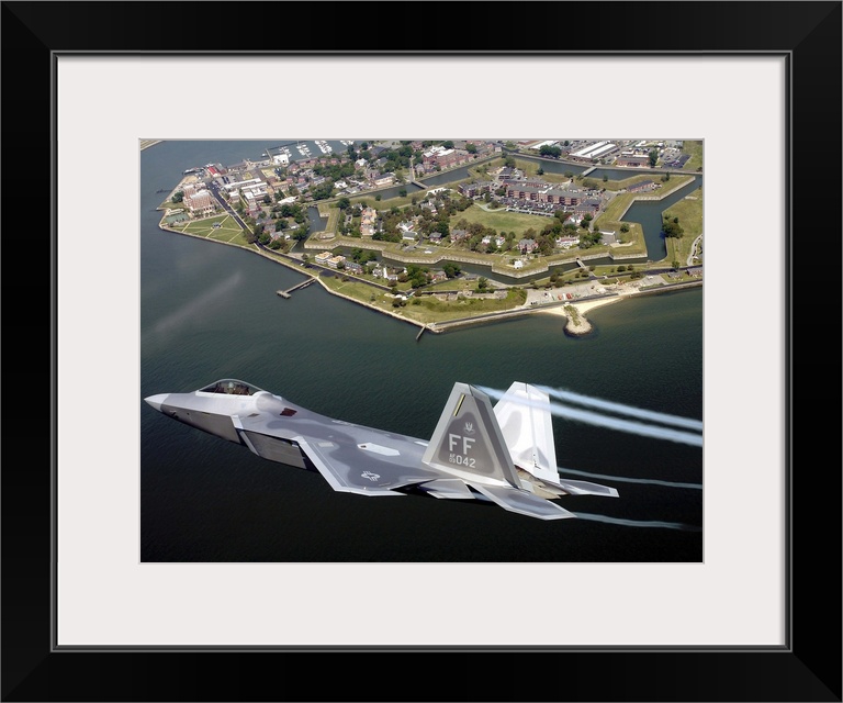 A militarty fighter jet flies past Fort Monroe with water vapor trails shooting from the wings of the plane.