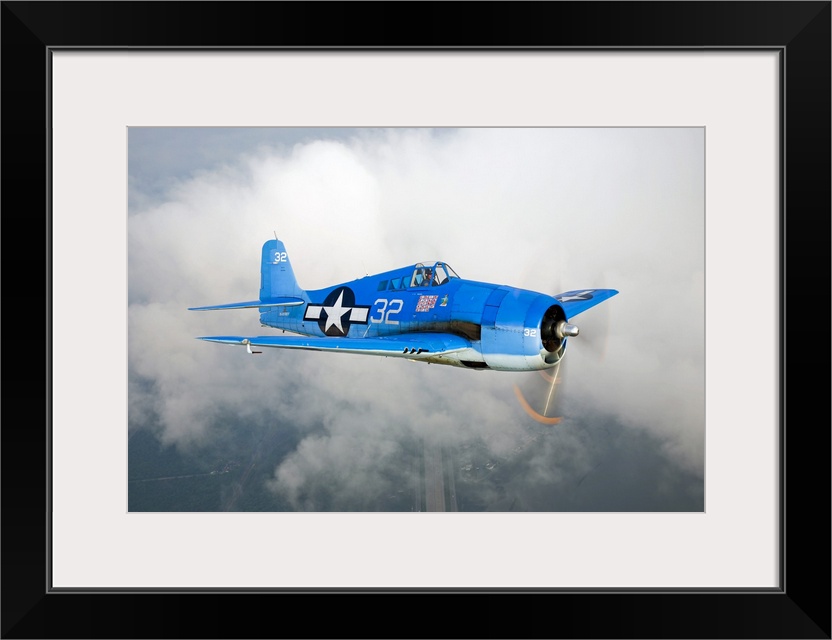 A vintage military aircraft is photographed high in the sky with a large cloud just behind it.