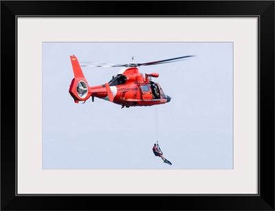 A rescue swimmer is lowered from a U.S. Coast Guard HH-65 Dolphin helicopter