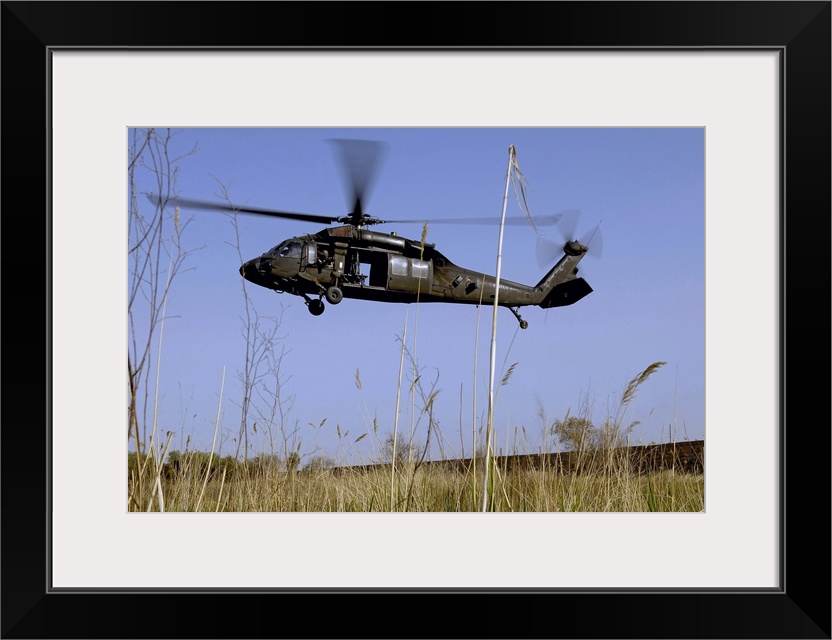 Photograph taken of a helicopter as it lifts off in a tall grass field.
