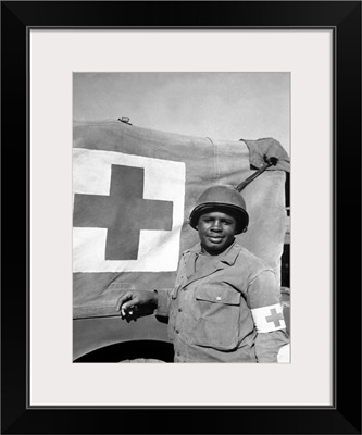 A World War II soldier stands next to his Red Cross vehicle