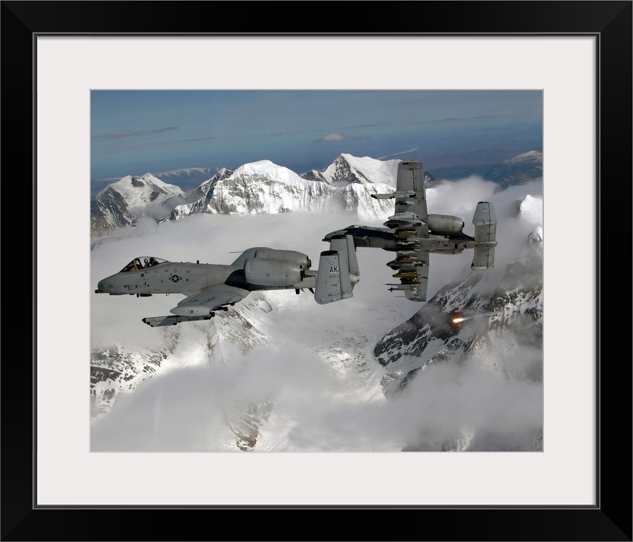 Big, horizontal photograph of two A10 Thunderbolt IIs flying through the clouds, above snow covered mountains.