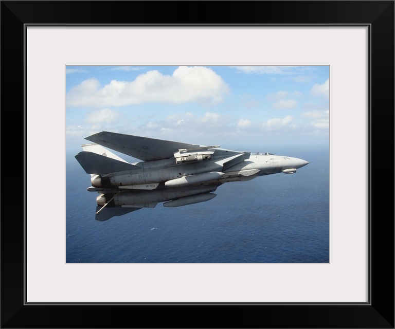 An F14D Tomcat banks with its tailhook lowered in preparation for landing