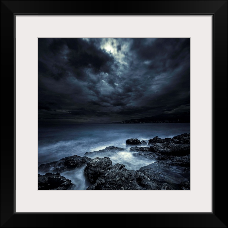 Black rocks protruding through rough seas with stormy clouds, Crete, Greece.