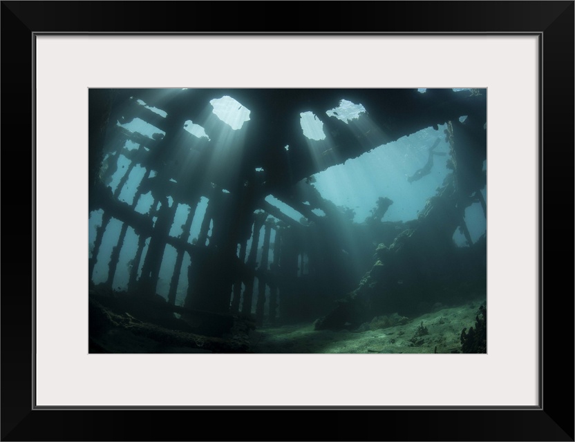 Bright sunlight pierces a shallow World War II shipwreck.