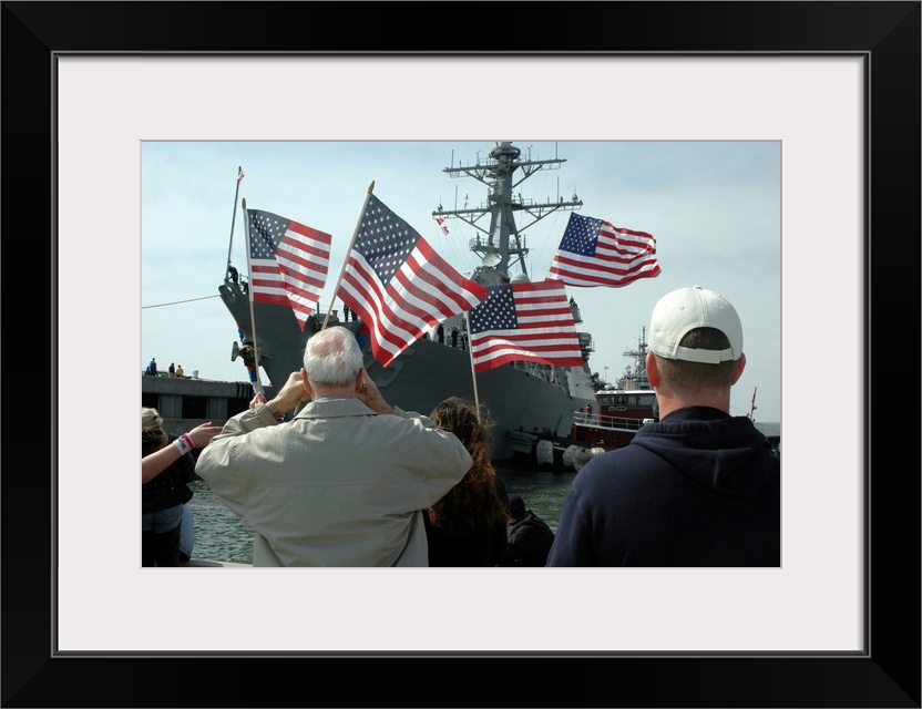 Norfolk, Virginia, March 9, 2006 - Family members wave American flags as they anxiously await their loved ones aboard the ...