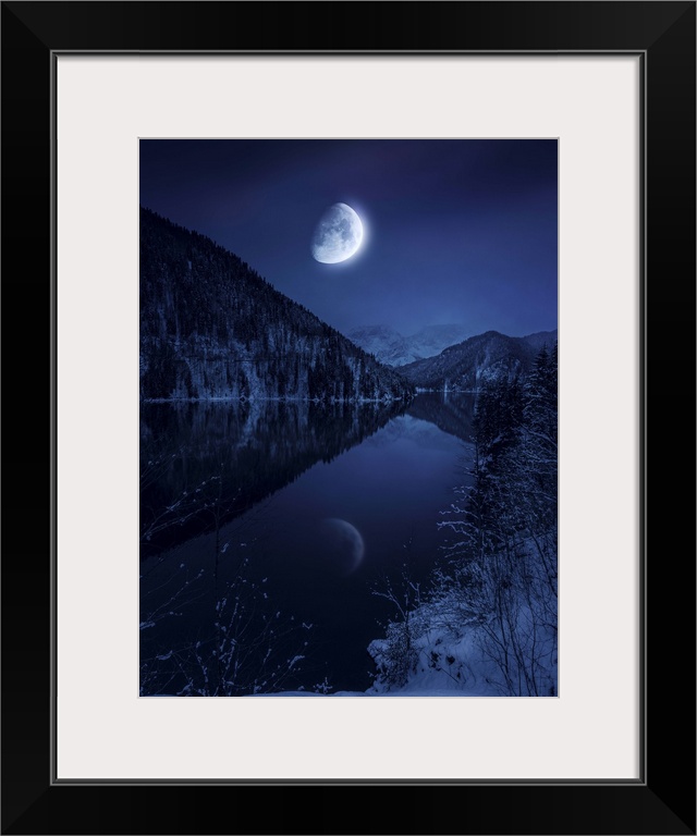 Moon rising over tranquil lake in misty mountains.