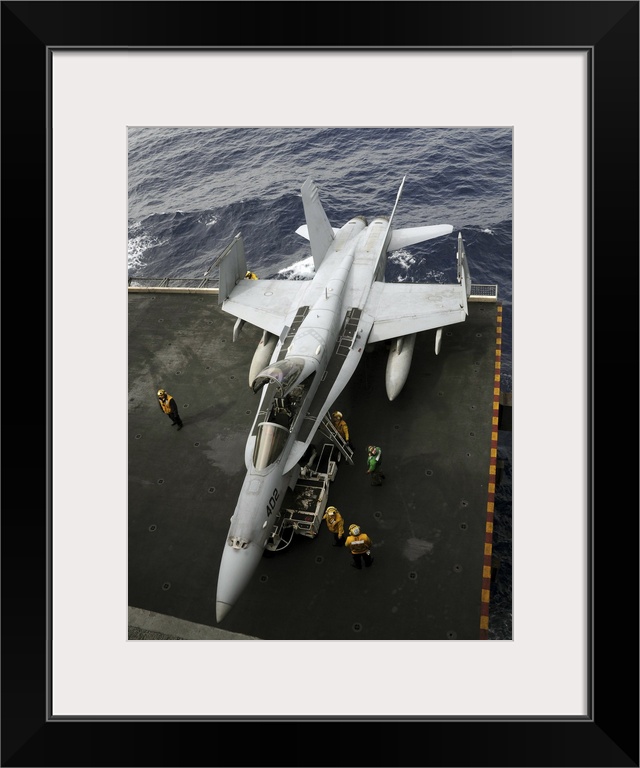 Pacific Ocean, March 2, 2011 - Sailors move an F/A-18C Hornet from the elevator into the hangar bay aboard USS Ronald Reagan.
