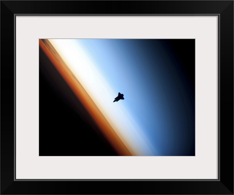 Silhouette of space shuttle Endeavour over Earths colorful horizon