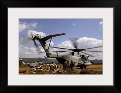 Soldiers And Sailors Help Pile Boxes Of Food And Water Off A CH-53E Helicopter