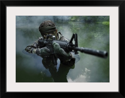 Special operations forces soldier transits the water armed with an assault rifle
