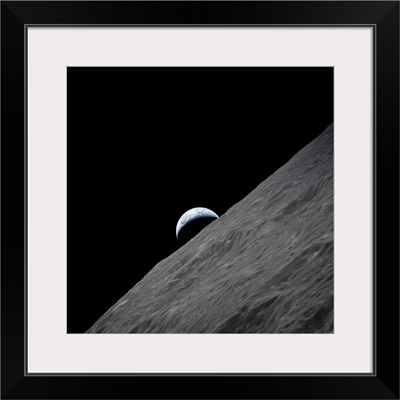 The crescent Earth rises above the lunar horizon