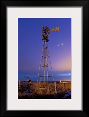 Venus and Jupiter are visible behind an old farm water pump windmill, Alberta, Canada