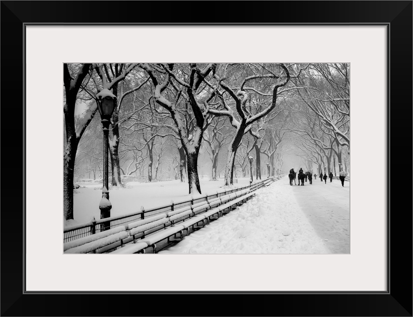 People walking along a snow-covered walkway under the trees in Central Park, New York.