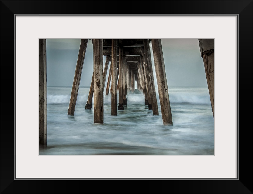 View from below of a wooden pier stretching out into the ocean.
