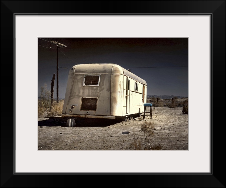 An old white caravan left to rot in the desert