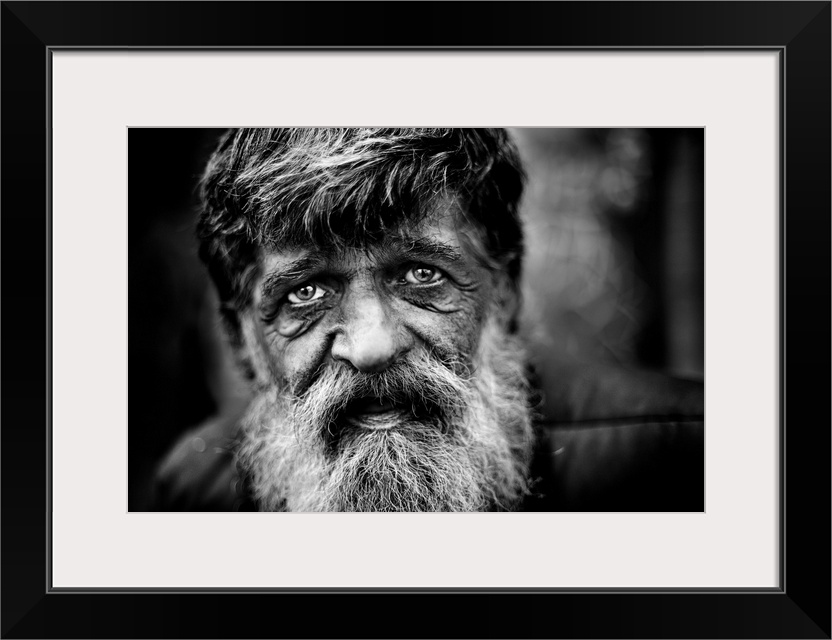 Close up of a mans face with a grey beard and tired eyes