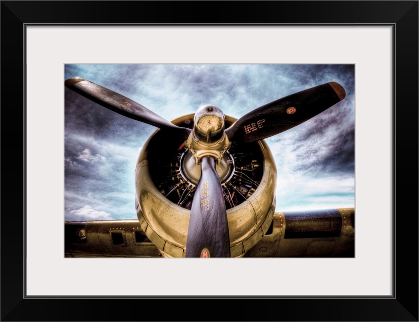 Front view photograph of vintage airplane with a dark cloudy sky in the background.