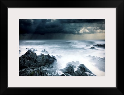 Stormy seascape with rough surf and dark clouds and rocks