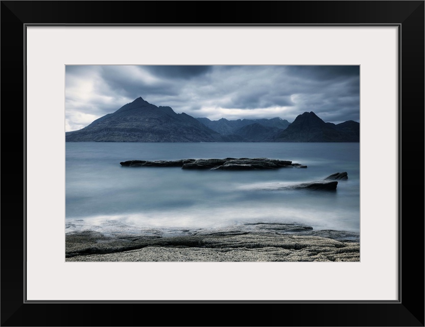 Looking across the sea to the Isle of Skye with mountains under a grey sky