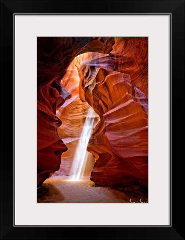 Photograph of the sun shining through the canyon top onto the sand in Antelope Canyon.