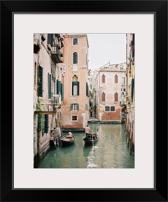 Photograph of a gondolier steering his way through the canals of Venice, Italy.