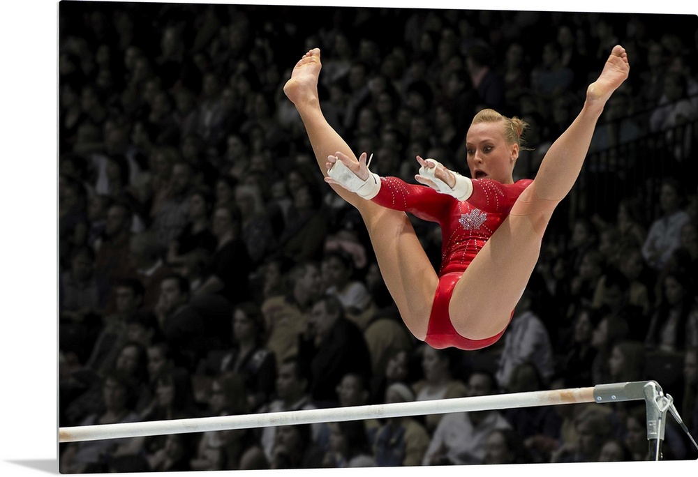 A female gymnast flies over the high bar with her legs raised up, arms outstretched ready to grab the bar.