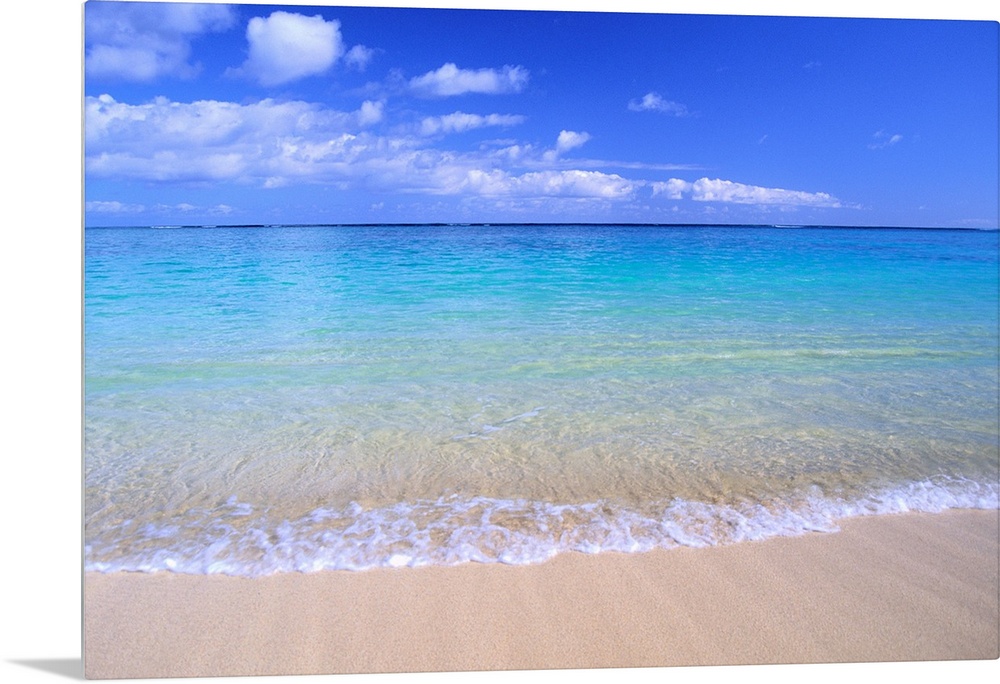 This home docor features a photograph that is a horizontal seascape of clean ocean water washing up on a sandy beach.