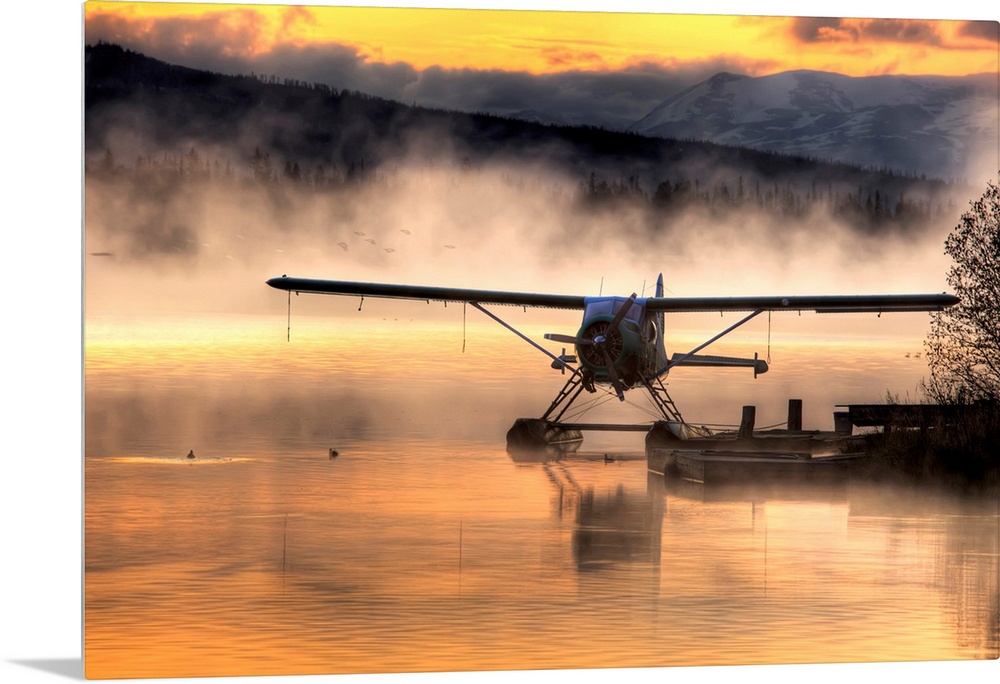 Giant photograph displays a seaplane sitting next to a dock as a soft fog rolls over the water.  In the background, the fa...
