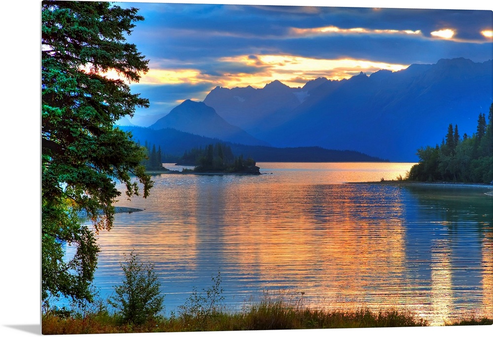 A landscape photograph of morning light reflecting on a lake in the mountains surrounded by trees.